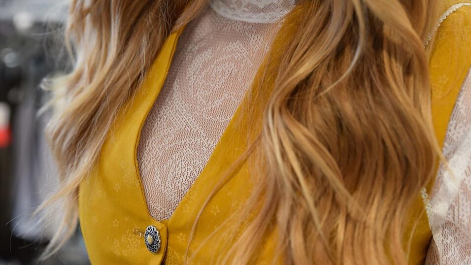 Das Vintage-Dirndl hat einen V-Ausschnitt. Die langärmelige Spitzenbluse ist hochgeschlossen.