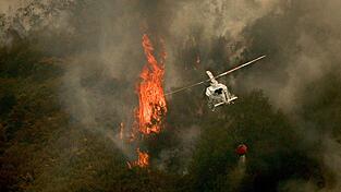 Ein Löschhubschrauber wirft Wasser über einem Feuer in der spanischen Provinz Ourense ab.