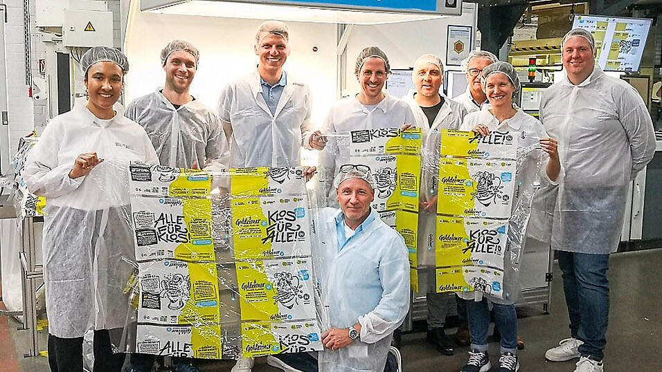 Mitarbeiter von Bischof+Klein, Wepa, Goldeimer und Wildplastic halten die bedruckte Goldeimer-Folie im Werk Konzell in der Hand.