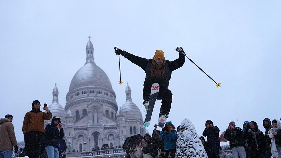 Ein Mann springt mit seinen Skiern den H&uuml;gel bei der Basilika Sacre-Coeur im franz&ouml;sischen Paris hinunter.