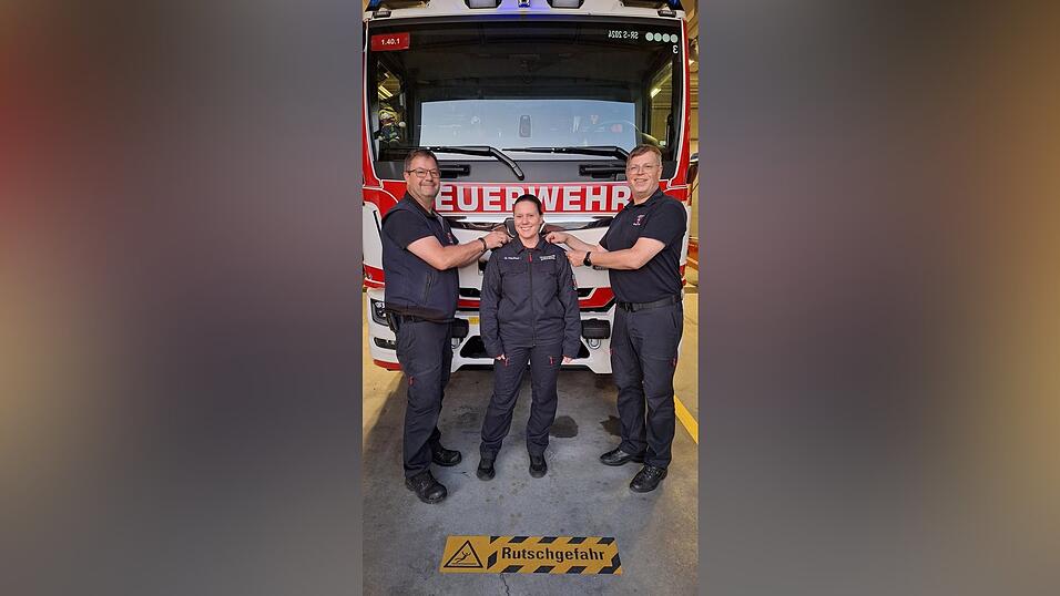 Stadtbrandinspektor Michael Schie&szlig;l (l.) und Stadtbrandrat Stephan Bachl bringen traditionsgem&auml;&szlig; die neuen Schulterklappen an und gratulieren Sabrina H&ouml;cherl zur L&ouml;schmeisterin.