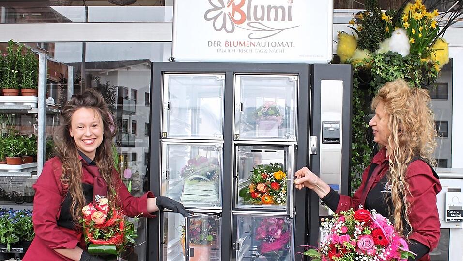 Roswitha (rechts) und Eva Kulzer bef&uuml;llen Blumi, den neuen Blumenautomaten. Er erm&ouml;glicht kontaktloses Einkaufen rund um die Uhr und ohne Wartezeiten.