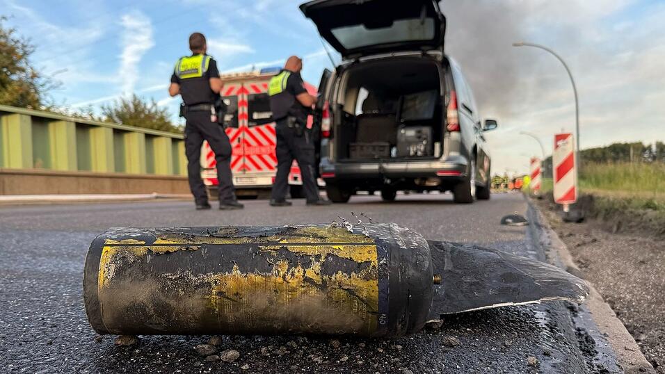Polizisten stehen hinter einem Metallbehälter. Trümmerteile sollen bei dem Brand Hunderte Meter weit geflogen sein.