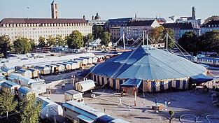 Roncalli mit seinem Zirkus-Zelt und Fuhrpark an dem Ort, wo alles angefangen hat: auf dem Areal der ehemaligen T&uuml;rkenkaserne zwischen T&uuml;rken-, Theresien- Gabelsberger- und Barer Stra&szlig;e, das jahrzehntelang als Parkplatz diente. Heute steht auf diesem Gel&auml;nde die Pinakothek der Moderne.