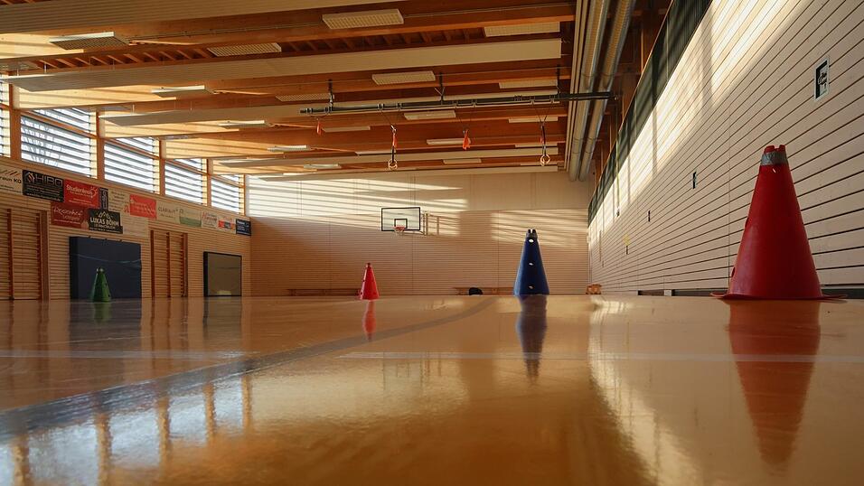 Wasserschaden in der SGM-Halle: Der Boden, bestehend aus einer Kunststoffschicht und zwei darunter liegenden Verbundplatten, ist uneben geworden. Der blaue Kegel im Foto wird von der W&ouml;lbung teilweise verdeckt.