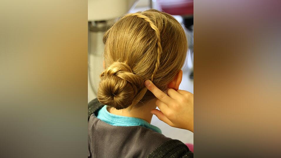 5. Die ausgelassene Str&auml;hne teilt sie in zwei Partien, verkordelt sie ineinander, legt sie quer &uuml;ber den Kopf und fixiert sie mit einer Haarnadel.