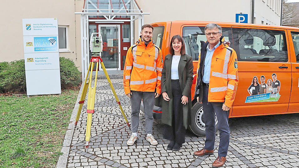 Markus Tschugg (l.), stellvertretender Amtsleiter, Stefanie Rimkus vom Rechtsamt der Stadt, und Johann Lerchenberger, Leiter des Amts für Digitalisierung, Breitband und Vermessung, stehen vor dem Vermessungsamt an der Wittelsbacherhöhe, neben sich ein Fahrzeug der Behörde mit Werbeaufdruck um Berufsnachwuchs sowie ein Vermessungsgerät, ein sogenannter Theomat.