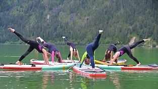 Redakteurin Ulrike (Mitte hinten) bei der Yoga-&Uuml;bung 'herabschauender Hund' auf dem SUP-Board. Bei sch&ouml;nem Wetter reichen auch normale Badeklamotten.