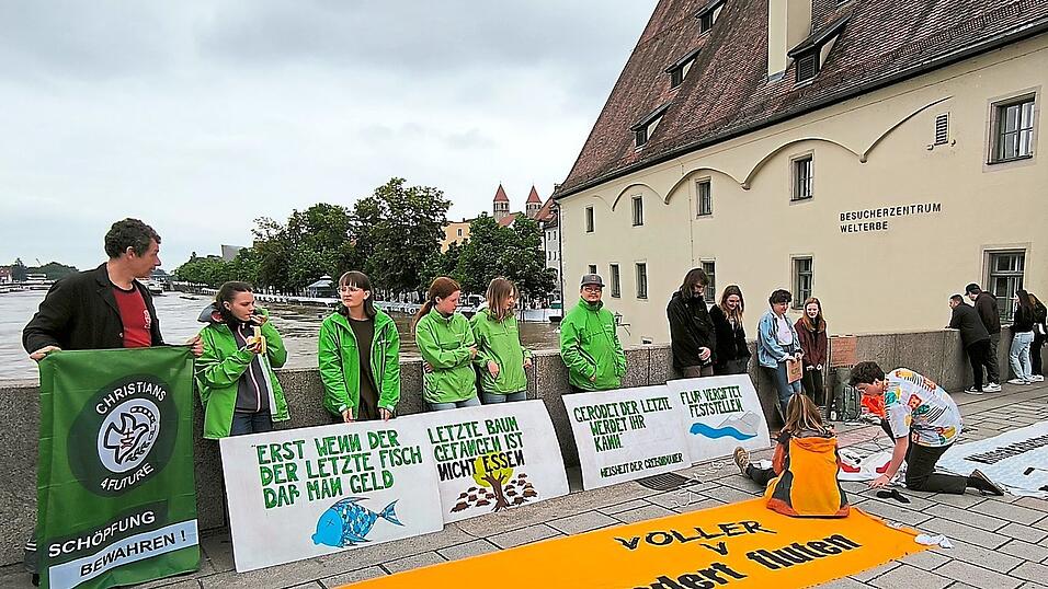 Aktivisten diverser Klimagruppen haben sich auf der Steinernen Br&uuml;cke zu einer Mahnwache versammelt. Mit Schildern und Bannern machten sie auf die Ursachen der Klimaver&auml;nderungen und Flut aufmerksam.
