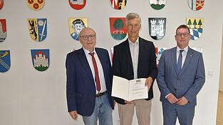 Die kommunale Dankurkunde überreichte Landrat Martin Neumeyer (l.) im Landratsamt im Beisein des Bürgermeisters Helmut Fichtner (r.) an Werner Maier (Mitte).