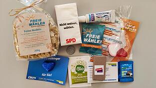 Geschenktüten und viele Kleinigkeiten: Tee, Zahnpasta, Tempos, Schokolade, Lineale, Nudeln, Stifte, Bonbons Gummibärchen, Einkaufswagenchips. Die Parteien versuchen mit vielen Kleinigkeiten, die Gunst der Wähler zu erhalten. Geschenktüten und viele Kleinigkeiten: Tee, Zahnpasta, Tempos, Schokolade, Lineale, Nudeln, Stifte, Bonbons Gummibärchen, Einkaufswagenchips. Die Parteien versuchen mit vielen Kleinigkeiten, die Gunst der Wähler zu erhalten.
