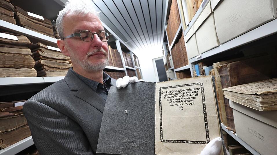 Memmingens Stadtarchivar Christoph Engelhard zeigt im Archiv eine Druckausgabe der «Zwölf Artikel» aus dem Jahr 1525. Mit dem Dokument forderten damals die Bauern mehr Rechte. Mit zahlreichen Veranstaltungen wird nun an die damalige Demokratiebewegung erinnert. (Archivbild)