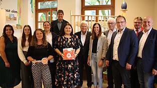 Krippenleiterin Stefanie Pöllmann (Sechste von links) und ihre Kolleginnen freuen sich mit der BRK-Familie um Vorsitzenden Theo Zellner (Siebter von links) und Bürgermeister Martin Stoiber (Dritter von rechts) über die neue Krippe. Als Geschenk gab es unter anderem ein BRK-Lätzchen.