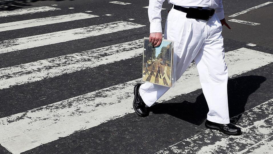 Einer der berühmtesten Zebrastreifen der Welt: Ein Fan trägt eine Ausgabe des Beatles-Albums «Abbey Road», als er die Abbey Road überquert. (Archivfoto) Einer der berühmtesten Zebrastreifen der Welt: Ein Fan trägt eine Ausgabe des Beatles-Albums «Abbey Road», als er die Abbey Road überquert. (Archivfoto)