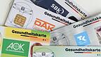 Gesundheitskarten verschiedener Krankenkassen liegen auf einem Tisch.