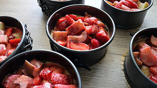 Erst den Teig, dann die Obstfüllung Schritt für Schritt in die Formen füllen.