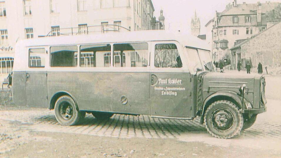 Der erste Bus der Firma Haider, Marke Eigenbau, auf dem Parkplatz des Mariandl in Straubing mit Paul Haider am Steuer. Im Hintergrund das Gebäude des Tanzcafés National.