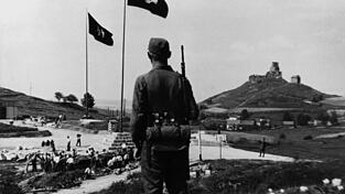 SS-Mann vor Landschaftskulisse bei der Errichtung des KZ Flossenbürg: eine Inszenierung von Macht und Kontrolle.