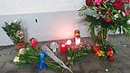 Blumen und Kerzen stehen auf dem Parkplatz, an dem die tote Frau im Kofferraum ihres Autos aufgefunden wurde.