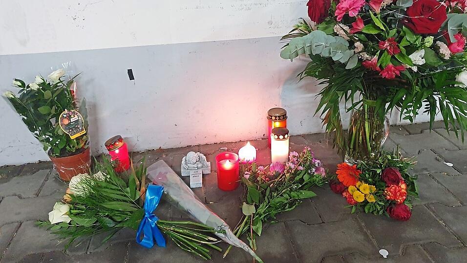 Blumen und Kerzen stehen auf dem Parkplatz, an dem die tote Frau im Kofferraum ihres Autos aufgefunden wurde.