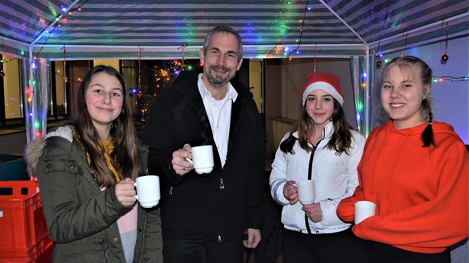 Schulleiter Stefan Renner zusammen mit Sch&uuml;lern am Gl&uuml;hweinstand.