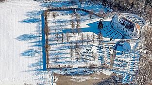 Der winterliche Friedhof aus der Luft mit den beiden Teilen von Kirche und Gemeinde und der Kirche St. Ulrich.