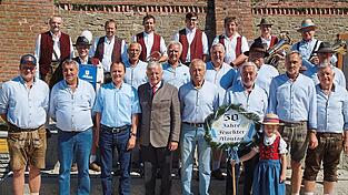 Die Mitglieder des Stammtisches Feuchter Montag beim Erinnerungsfoto nach dem Festgottesdienst, zusammen mit Pfarrer Matthias Kienberger, Bürgermeister Herbert Heidingsfelder, Taferlmaderl Maria Burgmeier und den Blasmusikern der Moosgrab'ntaler.