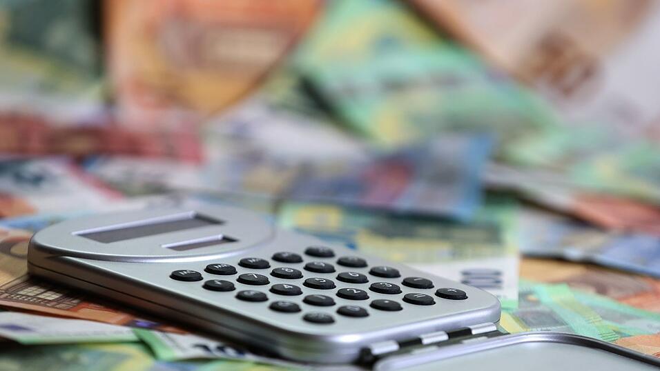 Ein Taschenrechner liegt auf verschiedenen Euro-Banknoten. (Symbolbild)