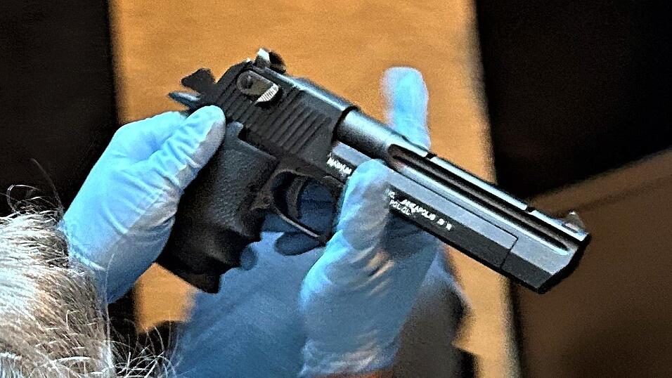 Ein Beamter nimmt eine aufgefundene Waffe in Augenschein. Hier handelt es sich wahrscheinlich um eine Dekowaffe.