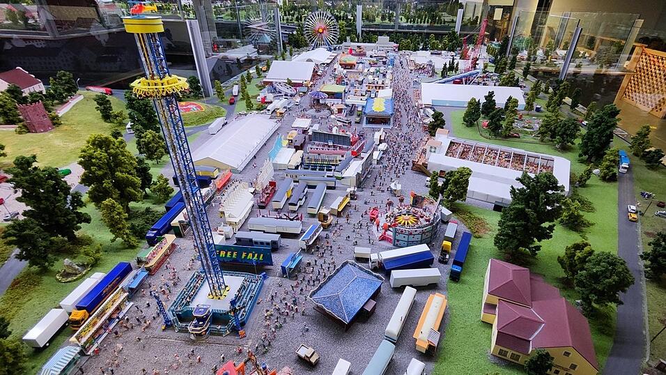 Hunderte von kleinen Volksfestbesuchern tummeln sich in der Miniaturanlage auf dem Festplatz des maßstabsgetreuen Modells. Hunderte von kleinen Volksfestbesuchern tummeln sich in der Miniaturanlage auf dem Festplatz des maßstabsgetreuen Modells.