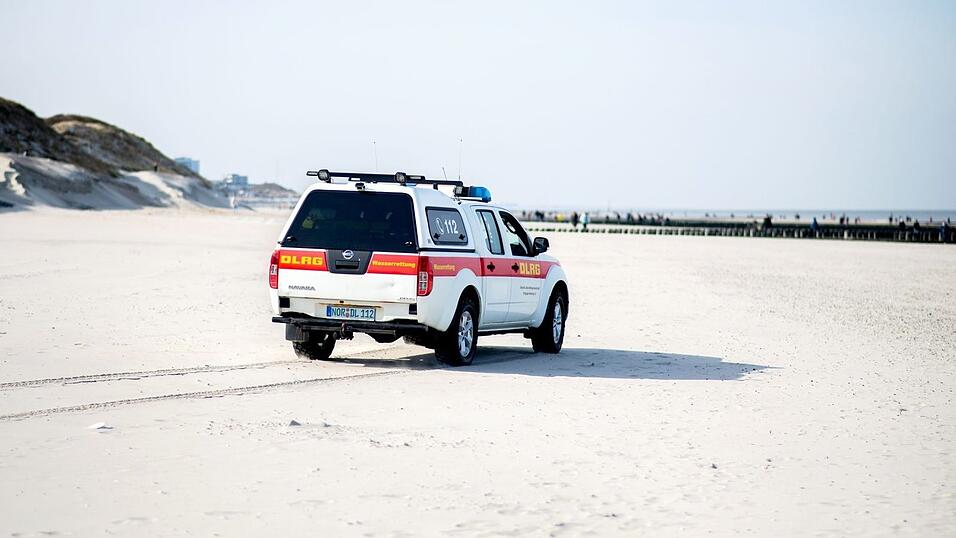 Ein Einsatzfahrzeug der DLRG Wasserrettung fährt über einen Strand. Ein Einsatzfahrzeug der DLRG Wasserrettung fährt über einen Strand.