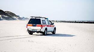 Ein Einsatzfahrzeug der DLRG Wasserrettung fährt über einen Strand. Ein Einsatzfahrzeug der DLRG Wasserrettung fährt über einen Strand.