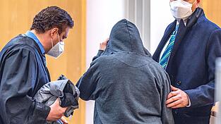 Die Angeklagte steht im Verhandlungssaal des Landgerichts zwischen ihren Verteidigern. Der 33 Jahre alten Frau wird vorgeworfen, ihre Mutter ermordet zu haben.