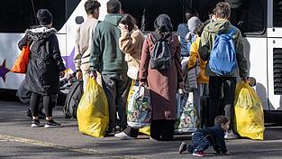 Flüchtlinge gehen in der hessischen Erstaufnahmeeinrichtung (HEAE) in Gießen zu einem wartenden Bus.