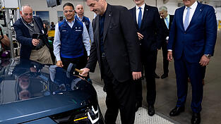 Markus S&ouml;der (CSU) bringt mit einem Hammer das BMW-Logo an einem Auto an. Hinter ihm stehen der k&uuml;nftige BMW-Chef Milan Nedeljkovi(&acute;c) (2. v. l.) und Werkleiter Robert Engelhorn (r.).