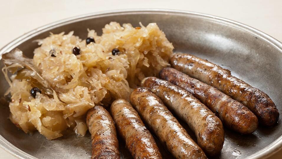 Bekannt f&uuml;r ihre geringe L&auml;nge: die N&uuml;rnberger Rostbratw&uuml;rste hier mit Sauerkraut und Meerrettich auf traditionellem Zinnteller dazu zwei Scheiben Brot.