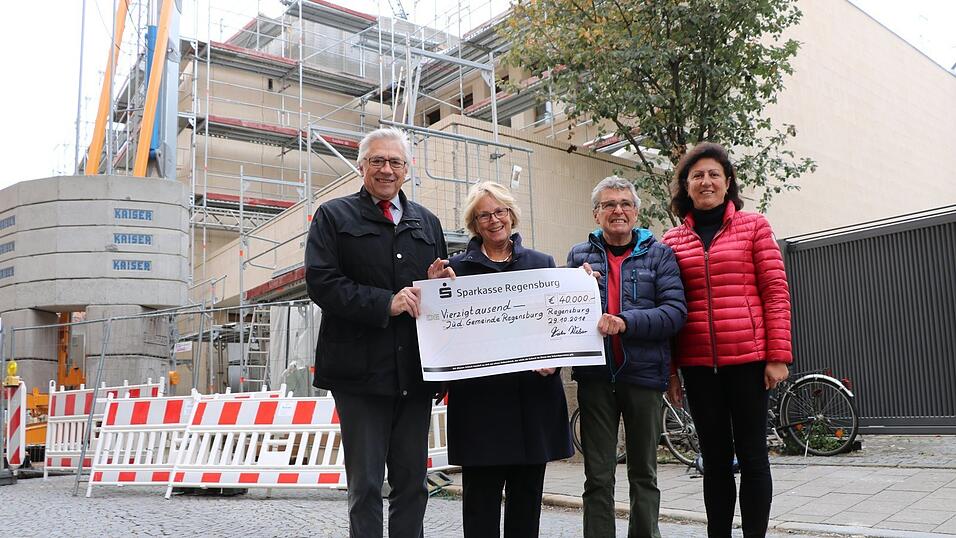 Professor Dr. Josef Eckstein vom F&ouml;rderverein (v.l.), Ilse Danzinger, Vorsitzende der J&uuml;dischen Gemeinde, Dieter Weber, F&ouml;rderverein, und Dorina Kuzenko, J&uuml;dische Gemeinde, mit dem symbolischen Scheck vor der neuen Synagoge.