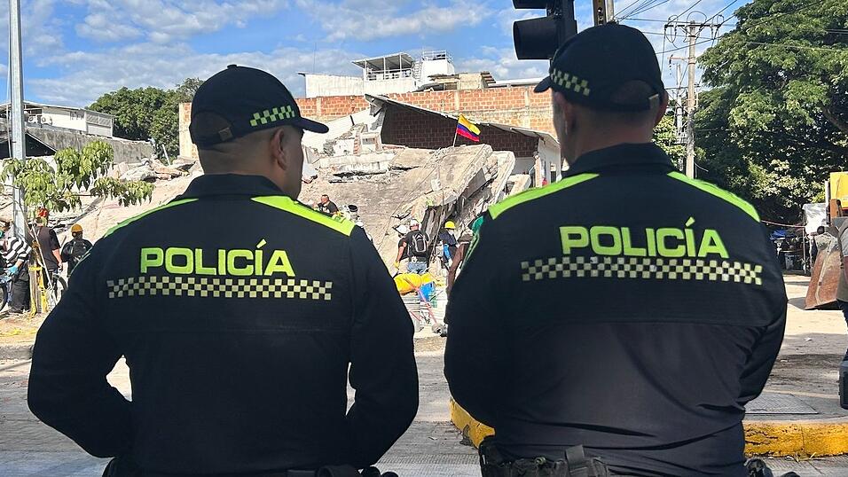 Polizisten stehen vor einem abgestürzten Gebäude. Polizisten stehen vor einem abgestürzten Gebäude.
