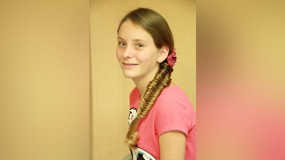 1. Celina zieht zuerst einen Seitenscheitel und nimmt alle Haare auf eine Seite. Um das sp&auml;tere Flechten zu erleichtern, fixiert sie den Zopf mit einem Gummi (muss aber nicht sein).