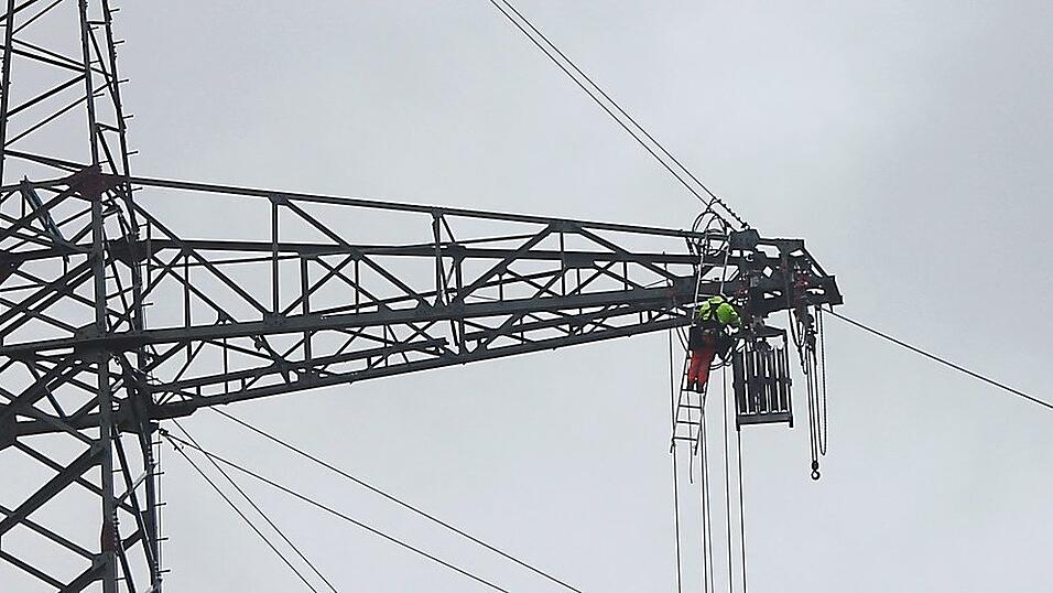 Ein Freileitungsmonteur arbeitet in 50 Metern H&ouml;he an einem Strommast.