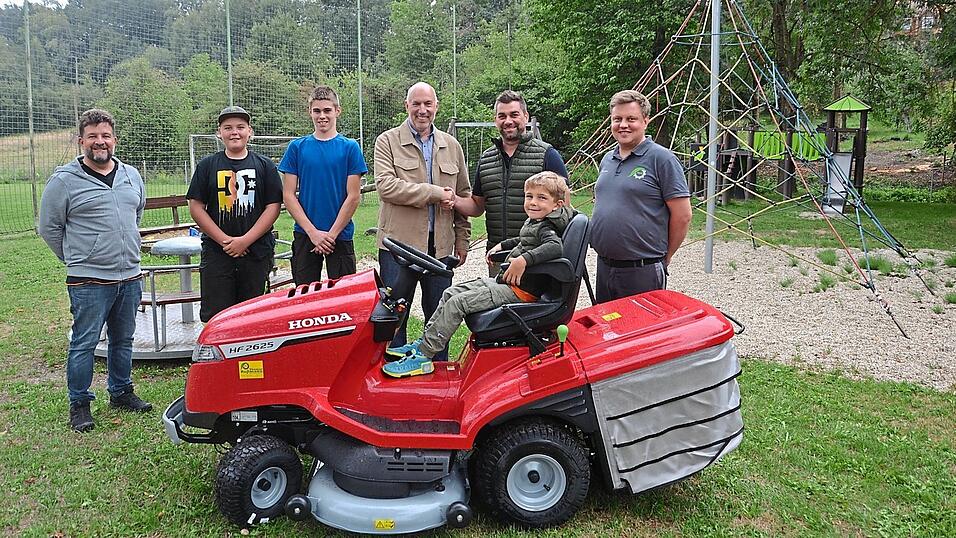 Thomas Ro&szlig;mann (rechts) lieferte den neuen Rasenm&auml;hertraktor der Spielplatzfreunde Osterwaal pers&ouml;nlich aus, auf dem Qurin Dreier schon einmal Platz nehmen durfte. Vereinsvorsitzender Michael Dreier bedankte sich bei B&uuml;rgermeister Holger Nick (v.r.) f&uuml;r die F&ouml;rderung aus der Marktkasse; daneben warten schon die beiden Rasenm&auml;herfahrer Julian Gruber und Hannes Steger mit dem Vereinsmitglied Marco Volpe auf ihren Einsatz.