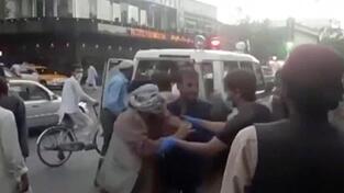 Menschen k&uuml;mmern sich um eine verwundete Person in der N&auml;he der Explosion au&szlig;erhalb des Flughafens in Kabul.