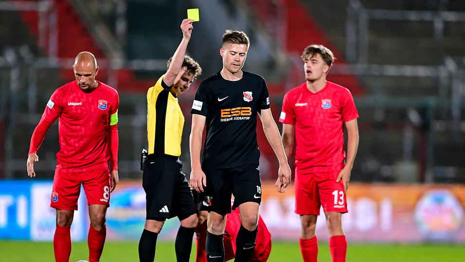 Im Duell mit Unterhaching (in Rot) kommt die SpVgg Hankofen (in Schwarz) - wie hier Lukas K&auml;ufl, der die gelbe Karte sieht, - immer einen Schritt zu sp&auml;t.