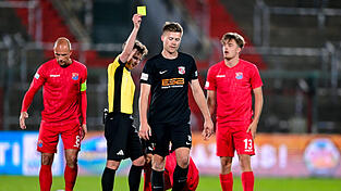 Im Duell mit Unterhaching (in Rot) kommt die SpVgg Hankofen (in Schwarz) - wie hier Lukas K&auml;ufl, der die gelbe Karte sieht, - immer einen Schritt zu sp&auml;t.