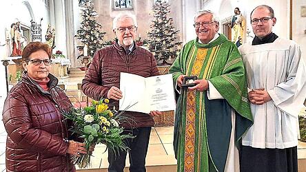 Pfarrer Wolfgang Häupl und die Pfarrgemeinderäte Emmi Bauer sowie Thomas Bauer überreichen Medaille und Urkunde an den verdienten Kirchenpfleger Walter Urban.