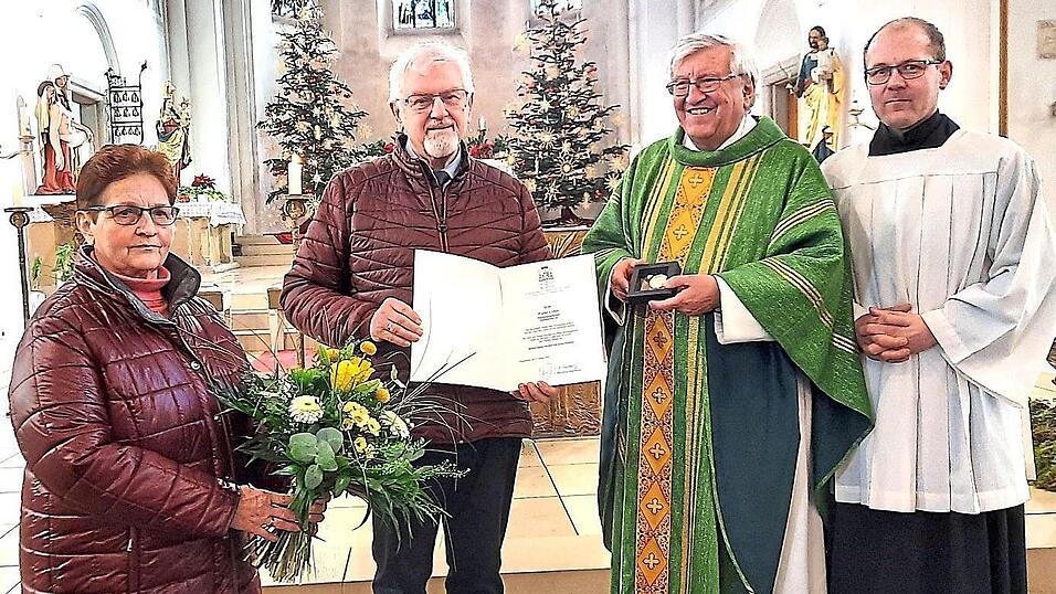 Pfarrer Wolfgang Häupl und die Pfarrgemeinderäte Emmi Bauer sowie Thomas Bauer überreichen Medaille und Urkunde an den verdienten Kirchenpfleger Walter Urban.