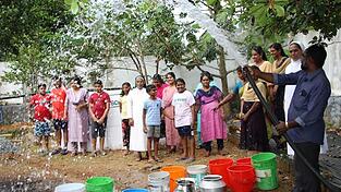 Die Menschen zeigen sich glücklich über die feierliche Übergabe eines Brunnens.