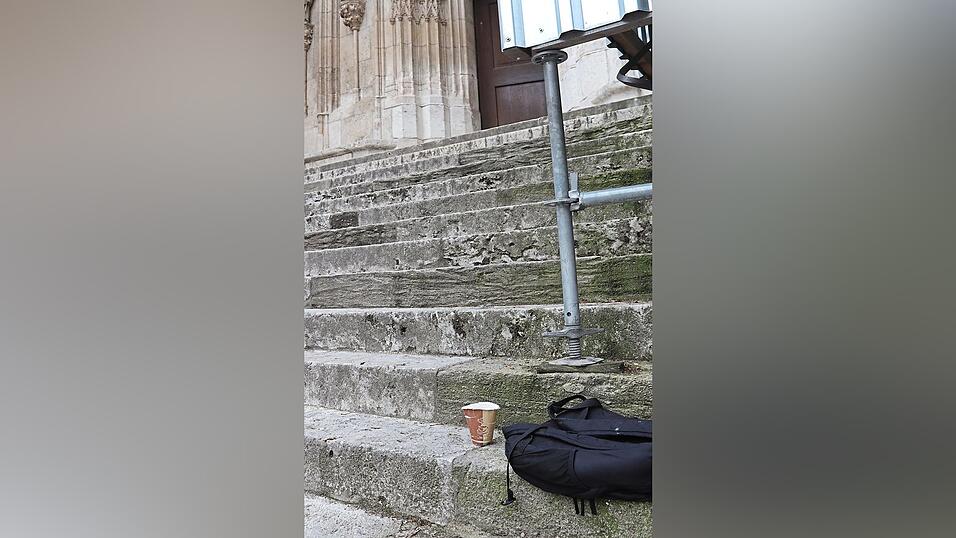 Der Pappbecher einer Bettlerin auf den Stufen vorm Dom.