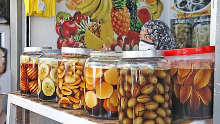 Die Marktfrau verschwindet beinahe hinter ihren mehrere Liter fassenden Gläsern: Auf Mauritius werden Gurken, Ananas und sogar Kartoffeln in Essig eingelegt. Bei einer Streetfood-Tour kann man davon probieren.
