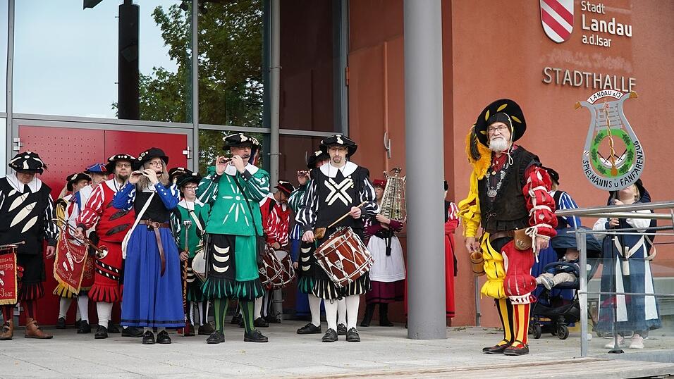 Werner H&ouml;henberger f&uuml;hrte w&auml;hrend des Konzerts durch die 100-j&auml;hrige Geschichte des Spielmannswesens in Landau, gekleidet war er dabei in den traditionellen Farben Rot und Wei&szlig; f&uuml;r Landau und Gelb und Schwarz, den Farben des Kaisers des Heiligen R&ouml;mischen Reiches deutscher Nation